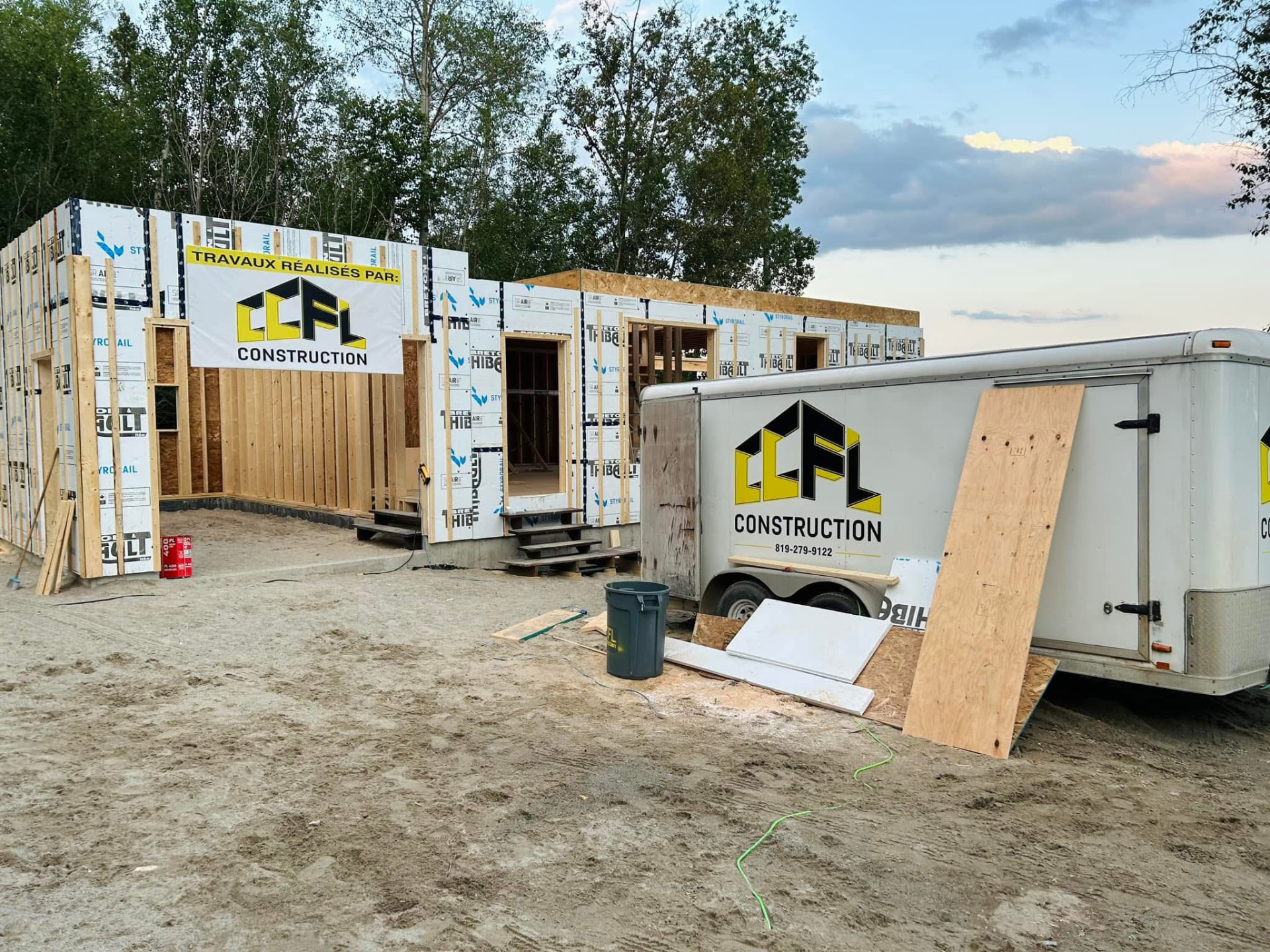 Chantier CCFL Construction : structure de bois en cours de montage, bannière « Travaux réalisés par CCFL Construction » et remorque de l'entreprise