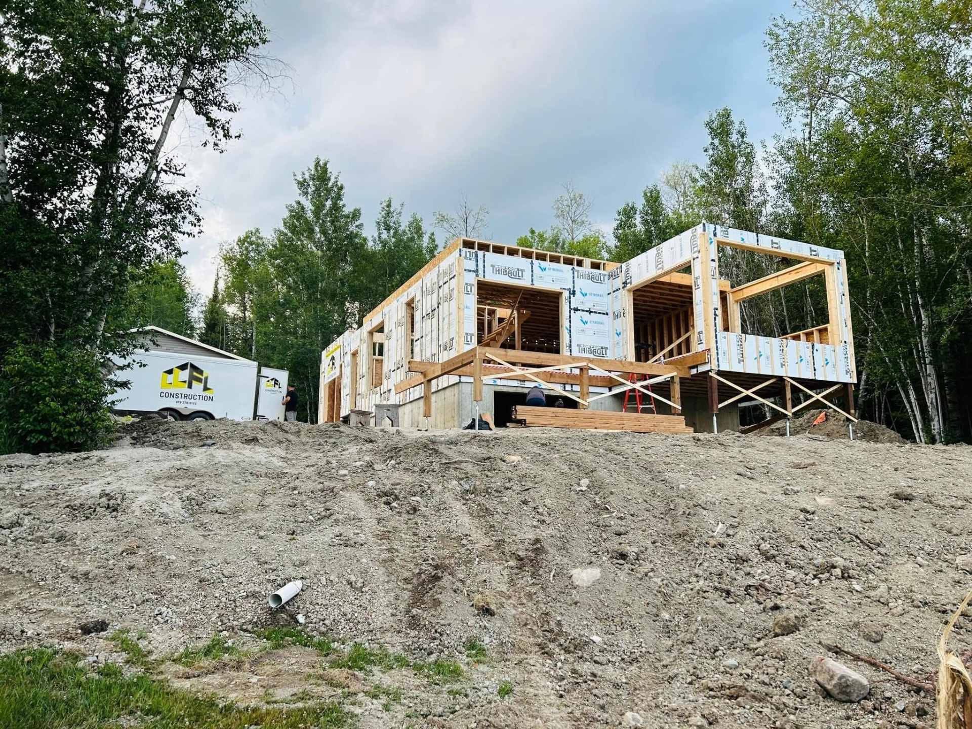 Chantier CCFL Construction en structure de bois dans un environnement boisé de Rouyn-Noranda, remorque de l'entreprise sur place