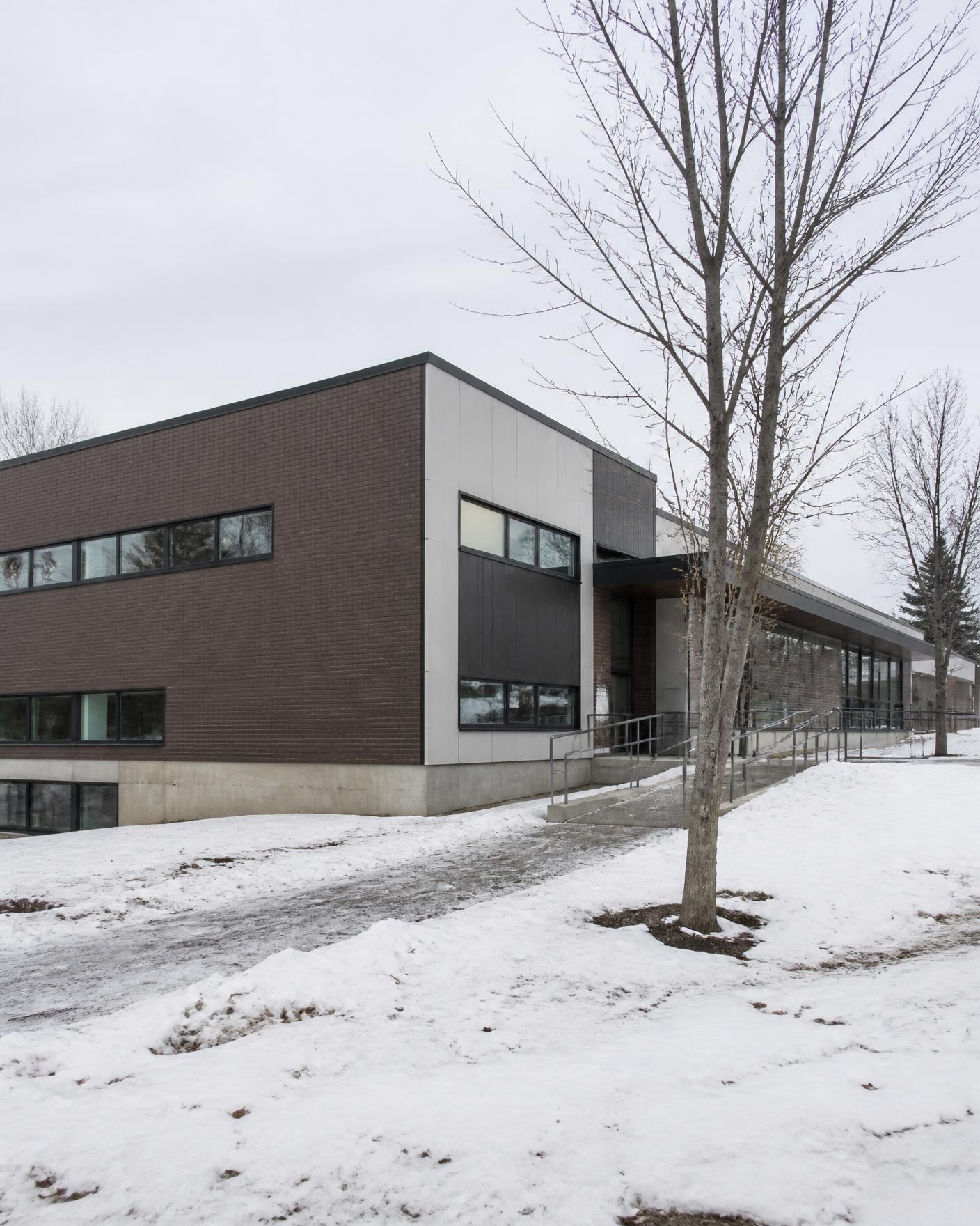 Bâtiment institutionnel en brique et panneaux, hiver québécois